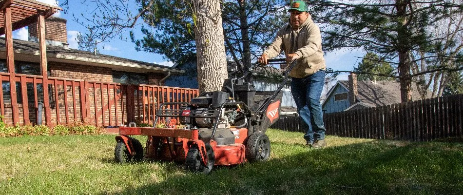 Worker pushing a lawn mower across a turf in Longmont, CO.