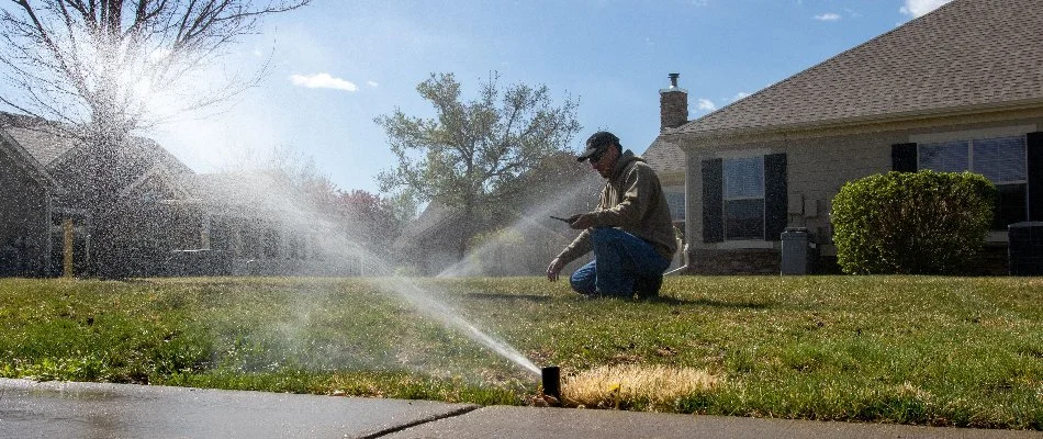 Professional inspecting irrigation sprinkler heads on a lawn in Longmont, CO.